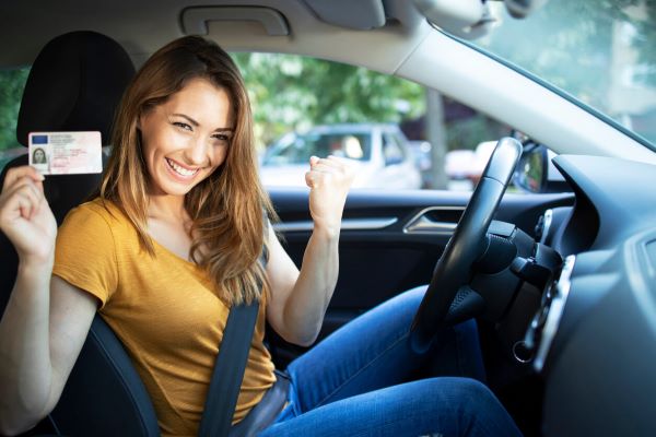 Happy driver in her car hodling a drivers license